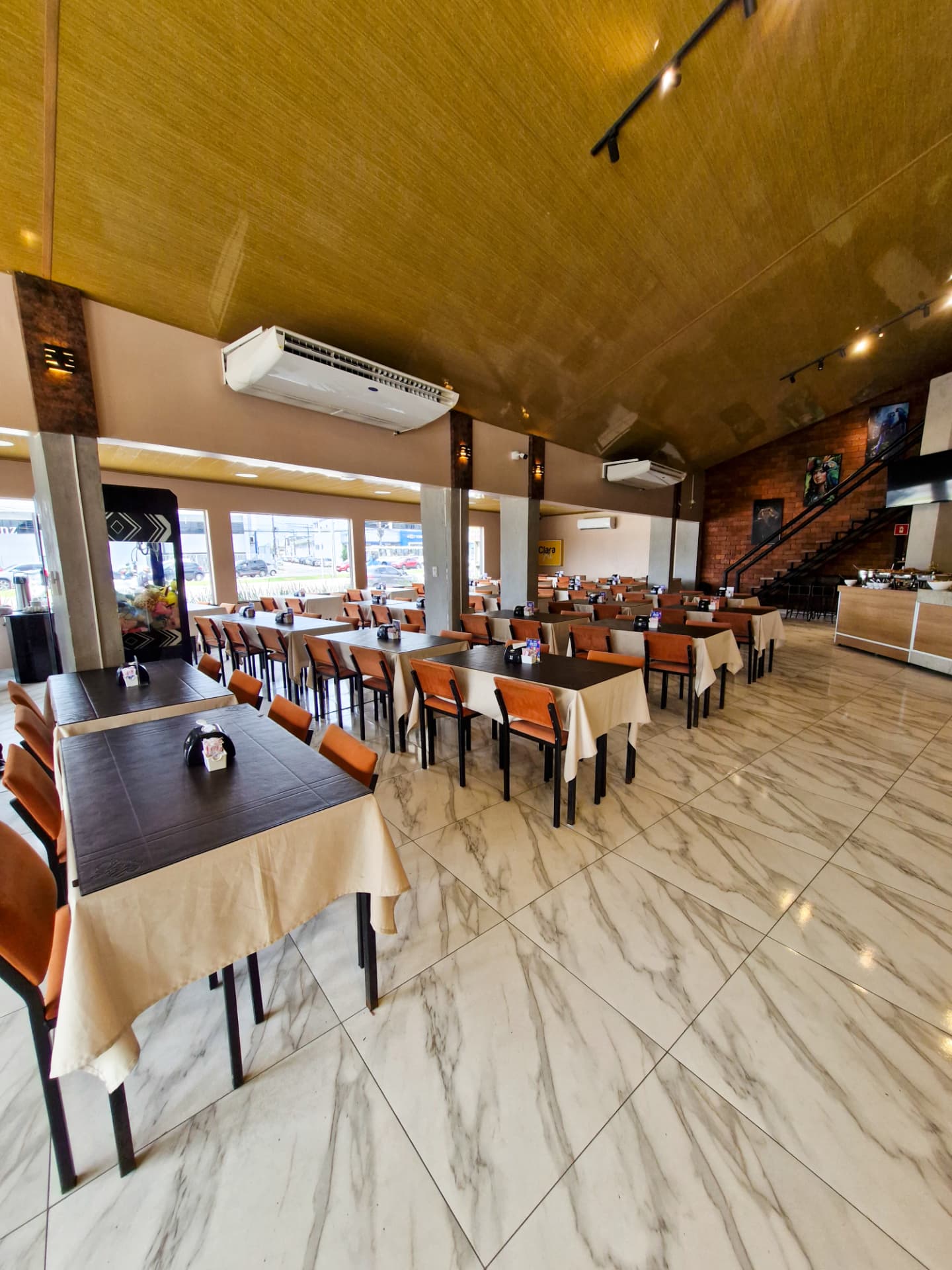 Salão amplo e climatizado com mesas postas na Clara Grill